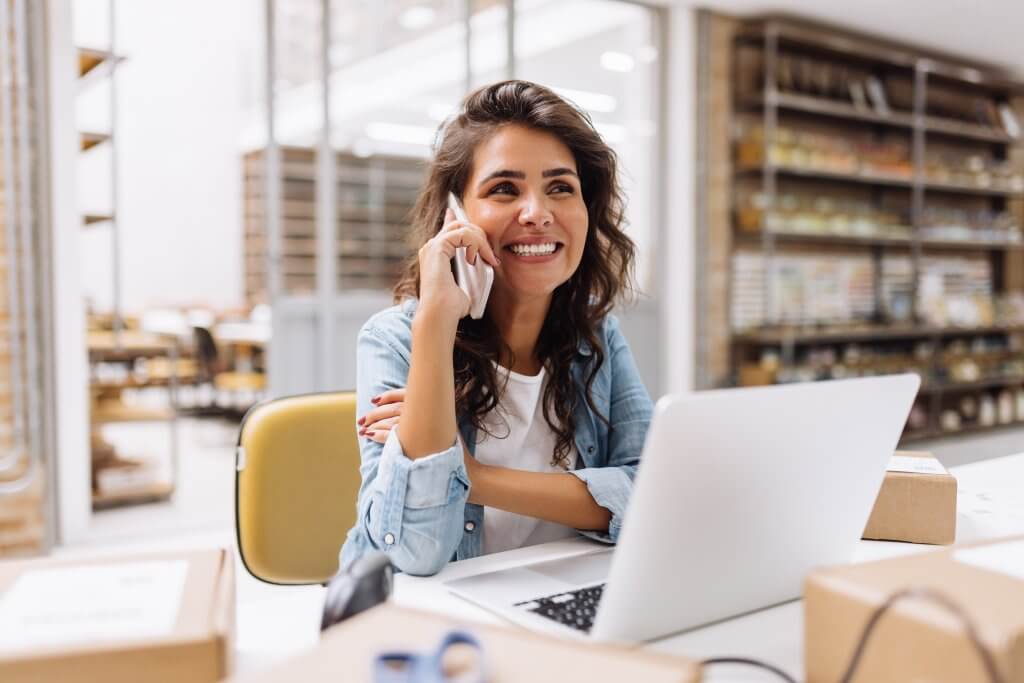 Cheerful,Businesswoman,Speaking,On,The,Phone,While,Working,In,A