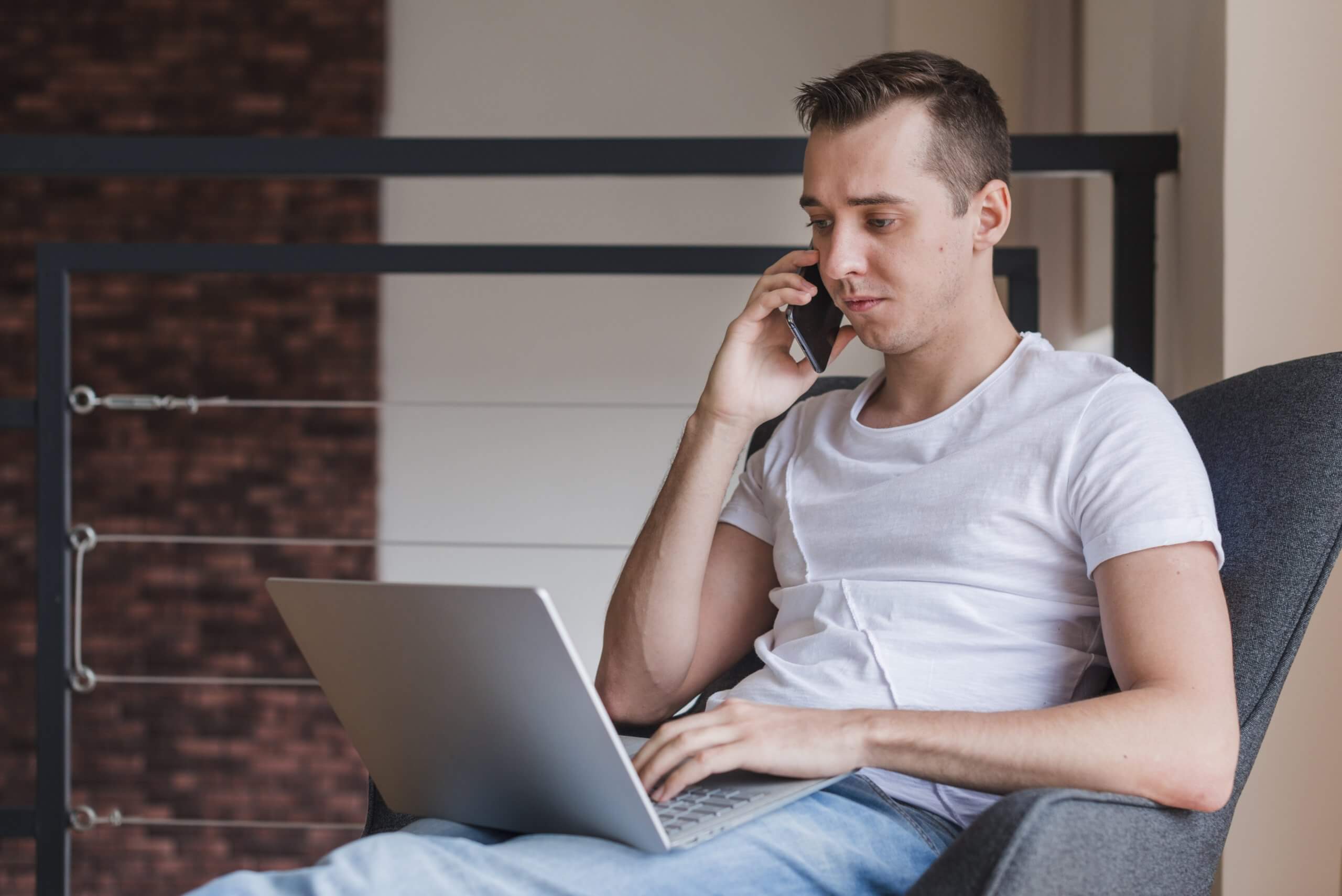 concentrated man talking smartphone sitting chair with laptop