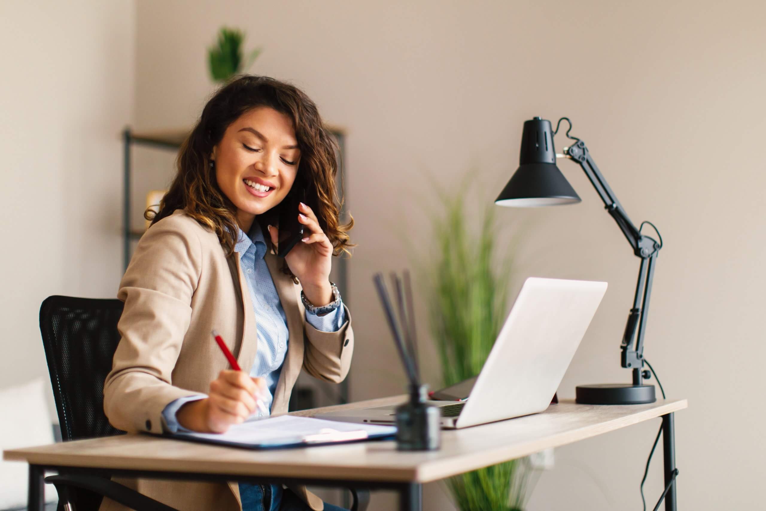 Young,Businesswoman,Talking,On,The,Mobile,Phone,And,Making,Notes