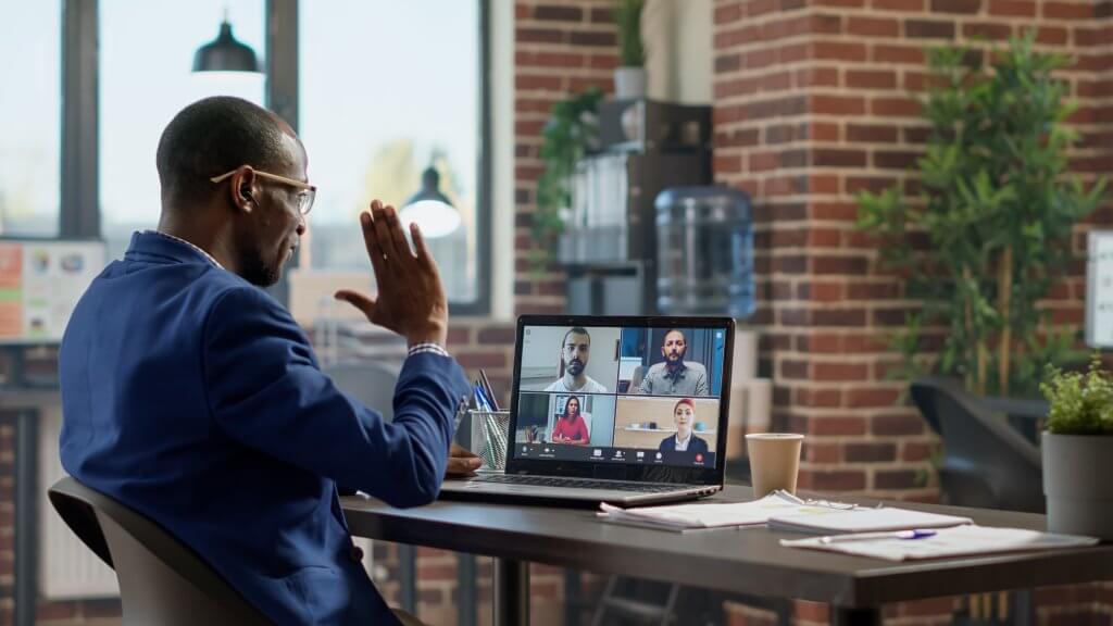 Young,Businessman,Attending,Teleconference,Meeting,On,Laptop,,Talking,To,Colleagues