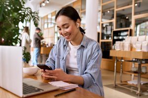 Young,Smiling,Asian,Woman,Student,Using,Smartphone,For,Elearning,Wearing